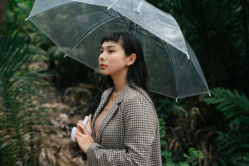 Asian business woman in formal shirt holding transparent umbrella.