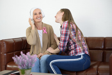 Senior breast cancer patient and her daughter use headphones to enjoy music, Cancer concept