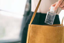 COVID-19 Hand Sanitizer Woman Using Small Sanitiser Bottle In Bag When Going Out Walking To Work In Public For Washing Hands Disinfecting With Alcohol Gel Dispenser.
