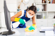 © JackF - Positive young kazhahstani woman wearing uniform and mask cleaning at company office ..
