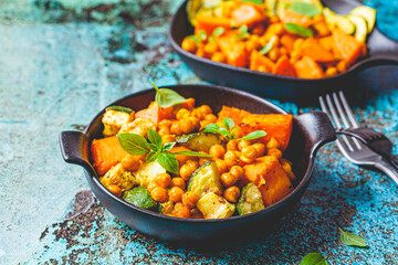 Wall Mural - Baked sweet potato, zucchini and chickpeas in cast iron pan, blue background. Baked vegetables. Healthy food concept.