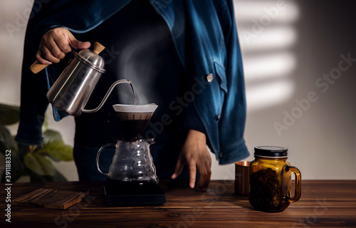 Person Dripping Coffee at Home in the Morning. Zen and Cozy Living. Pouring Hot Water from Kettle into a Dripper. Medium shot