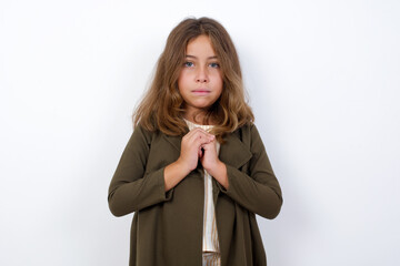 Wall Mural - Sad Beautiful little girl standing against white background,  feeling upset while spending time at home alone staring at camera with unhappy or regretful look.