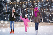 © Syda Productions - christmas, family and leisure concept - happy mother, father and daughter at outdoor skating rink in winter over snow
