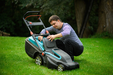 Down syndrome adult man mowing lawn outdoors in backyard, helping with housework concept.