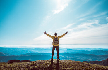 Wall Mural - Successful man with arms up on the top of the mountain - Hiker on the cliff raising hands to the sky.