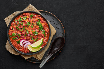 Rajma Masala Curry in black bowl on dark slate table top. Red Kidney Bean Dal is indian cuisine vegetarian dish. Asian food, meal. Top view. Copy space