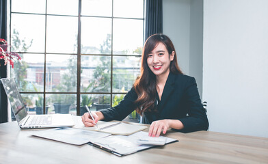 Portrait of smiling young businesswoman using laptop sitting at her desk. 