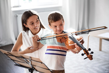 Canvas Print - Young woman teaching little boy to play violin indoors