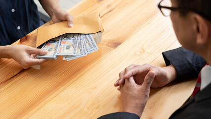 Businessman reciving money United States Dollars bills to corruption from his partner in business at working desk - bribery concept.