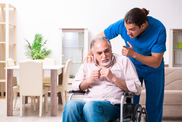 Old man in wheel-chair and young bad caregiver indoors