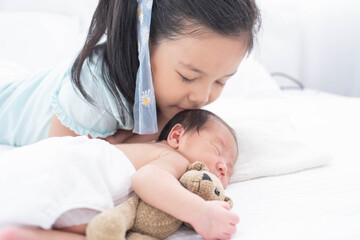 Canvas Print - little sister hugging her newborn brother. toddler kid meeting new sibling. love, trust and tenderness. cute girl and new born baby boy relax in a white bedroom. family with children at home.