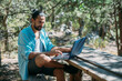 © Anna - Male tourist working on a laptop outdoors in a camping.