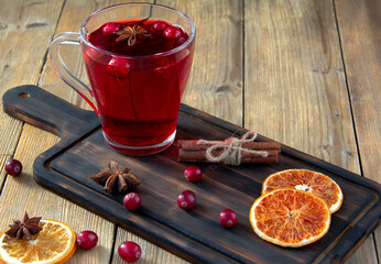 Wall Mural - Drink from fresh cranberries in a glass on a dark wooden cutting Board. Orange slices, cinnamon and anise on a wooden table. The idea of winter vitamin drinks.