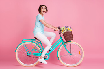 Poster - Full length photo of exited surprised lady dressed casual outfit sitting bike wild flowers isolated pastel pink color background