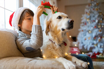 Canvas Print - Boy and his dog enjoying Christmas together at home 
