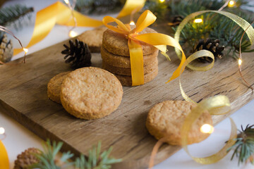 Wall Mural - Parmesan cookies with yellow ribbon on wooden background with fir and garland