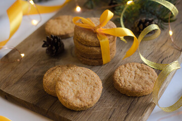 Wall Mural - Parmesan cookies with yellow ribbon on wooden background with fir and garland