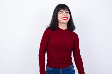 Beautiful young Caucasian woman standing against white background blinking eyes with pleasure having happy expression. Facial expressions and people emotions concept.