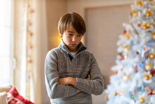 Unhappy Boy Standing By Christmas Tree
