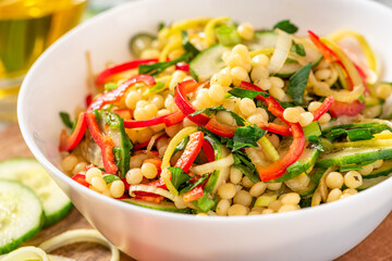 Sticker - Vegetable salad with ptitim close-up. Salad made from toasted pasta ptitim (petit plomb or Israeli couscous), cucumbers, peppers, onions, and parsley. Vegan food. Mediterranean and Israeli cuisine.