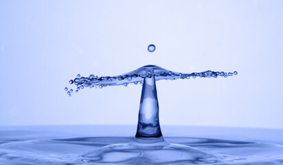 Water drop falling down. Abstract blue background.