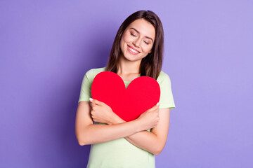 Wall Mural - Photo portrait of dreamy girl wearing green t-shirt hugging embracing red heart postcard isolated on vivid purple color background