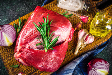 Wall Mural - Raw meat, beef fillet, large piece on a cutting board with spices for cooking. Black dark green background, copy space