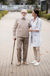 © LIGHTFIELD STUDIOS - social worker supporting aged man with walking stick while strolling together