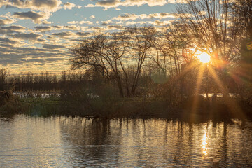 Wall Mural - autumn landscape, sunset over the lake, sun's rays and glare are visible, November, leaf fall season, landscape with autumn leaves and water