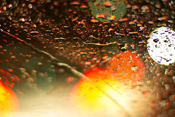 Car lights reflecting in a windshield full of rain drops