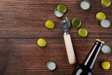 Bottle Caps With Bottle And Opener On Brown Wooden Table
