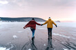 © Yakov Knyazev/Stocksy - Winter lake and a couple of young couple having fun - ice sliding without skates