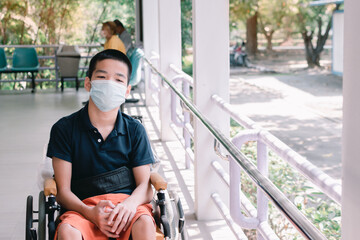 asian special child on wheelchair wearing a protection mask against pm 2.5 air pollution and flu cov