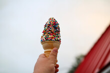 An Ice Cream Cone With Sprinkles In Someone's Hand