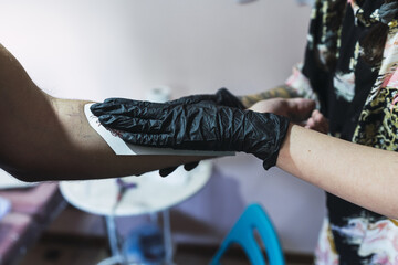 Wall Mural - Female tattoo artist tattooing a client's arm