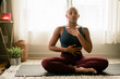 © Melissa Alexander/Creative Flame - Black woman breathing and doing meditation at home