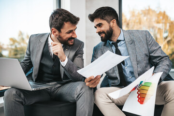 Two cheerful businessmen working together in office.