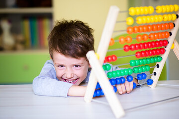 Joyful Caucasian toddler boy learning to count using the abacus