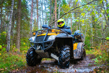 Man On A Quad Bike View From Below. ATV Is Standing In The Mud. ATV Rides Through The Woods. Biker On The Background Of The Forest. Concept - Off-road ATV Racing. Extreme Competitions.