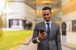 © Ranta Images - Happy African businessman outdoors smiling and using phone