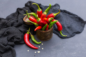 Sticker - Top view of the green and red hot chili peppers in a rusty cup with cloth on a dark tabletop