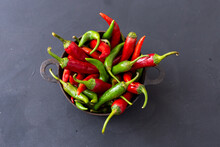 Top View Of The Green And Red Hot Chili Peppers In A Rusty Cup On A Dark Tabletop