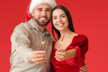 Poster - Young couple with Christmas sparklers on color background