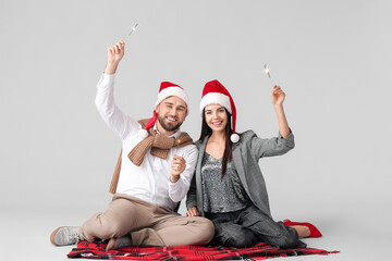 Poster - Young couple with Christmas sparklers on grey background