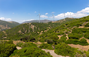 The mountain landscape in the south of Andalusia with many wind turbines on the hills. The wind farm is located on the Strait of Gibraltar. It is a summer day with sunshine.