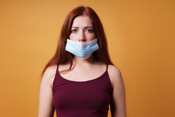 young woman wearing medical face mask wrong leaving nose uncovered - improper use of protective corona coronavirus covid mask