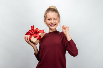 Portrait of happy blonde girl holding gift decorated with ribbon. Studio shot white background