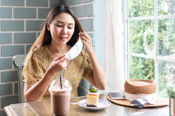 Happy young Asian woman take off medical mask before eating. Health care, new normal lifestyle concept. Closeup