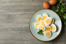 Plate with boiled eggs and parsley on gray background